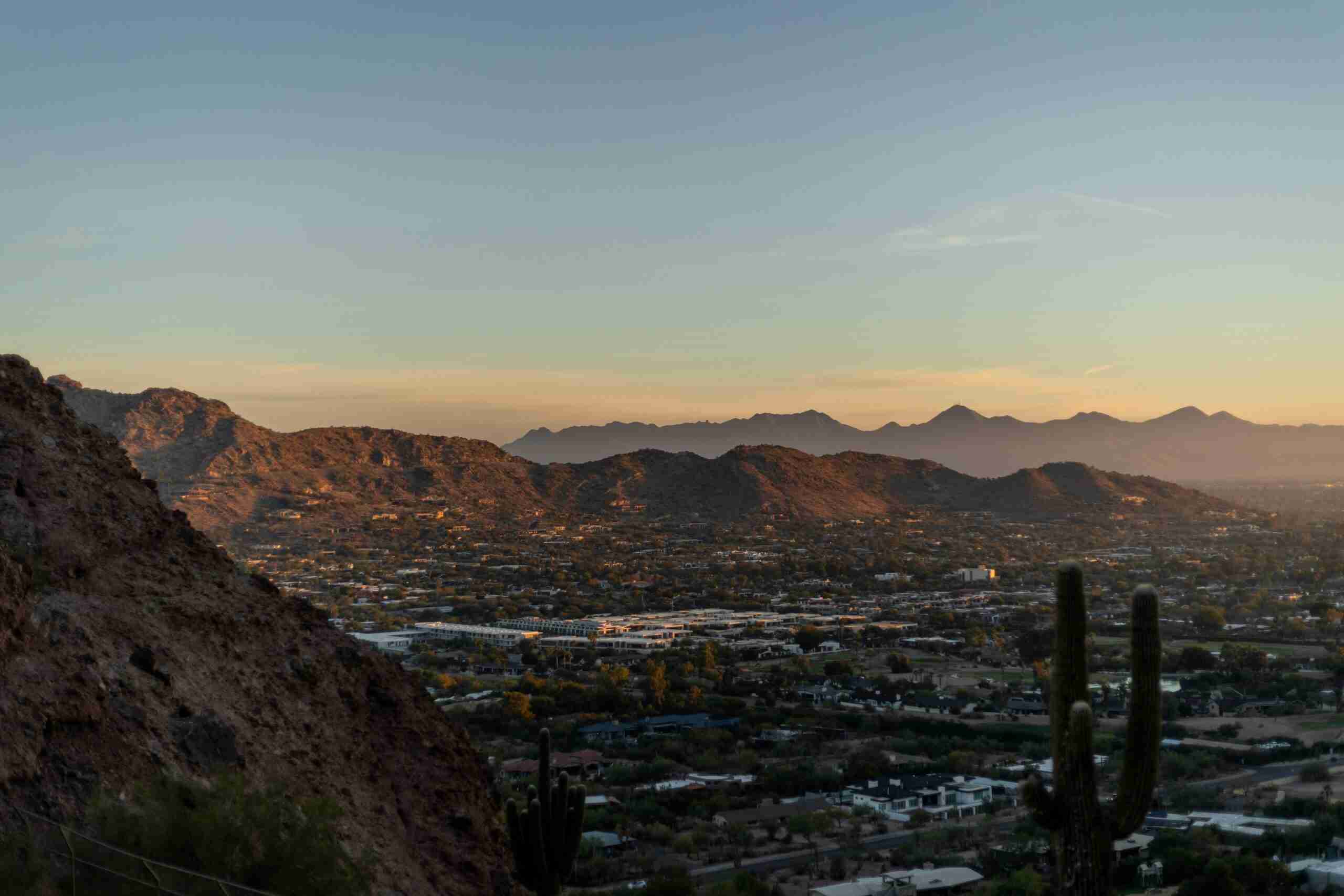 insurance crm Breathtaking view of Phoenix cityscape and desert mountains at sunset with silhouetted cacti.