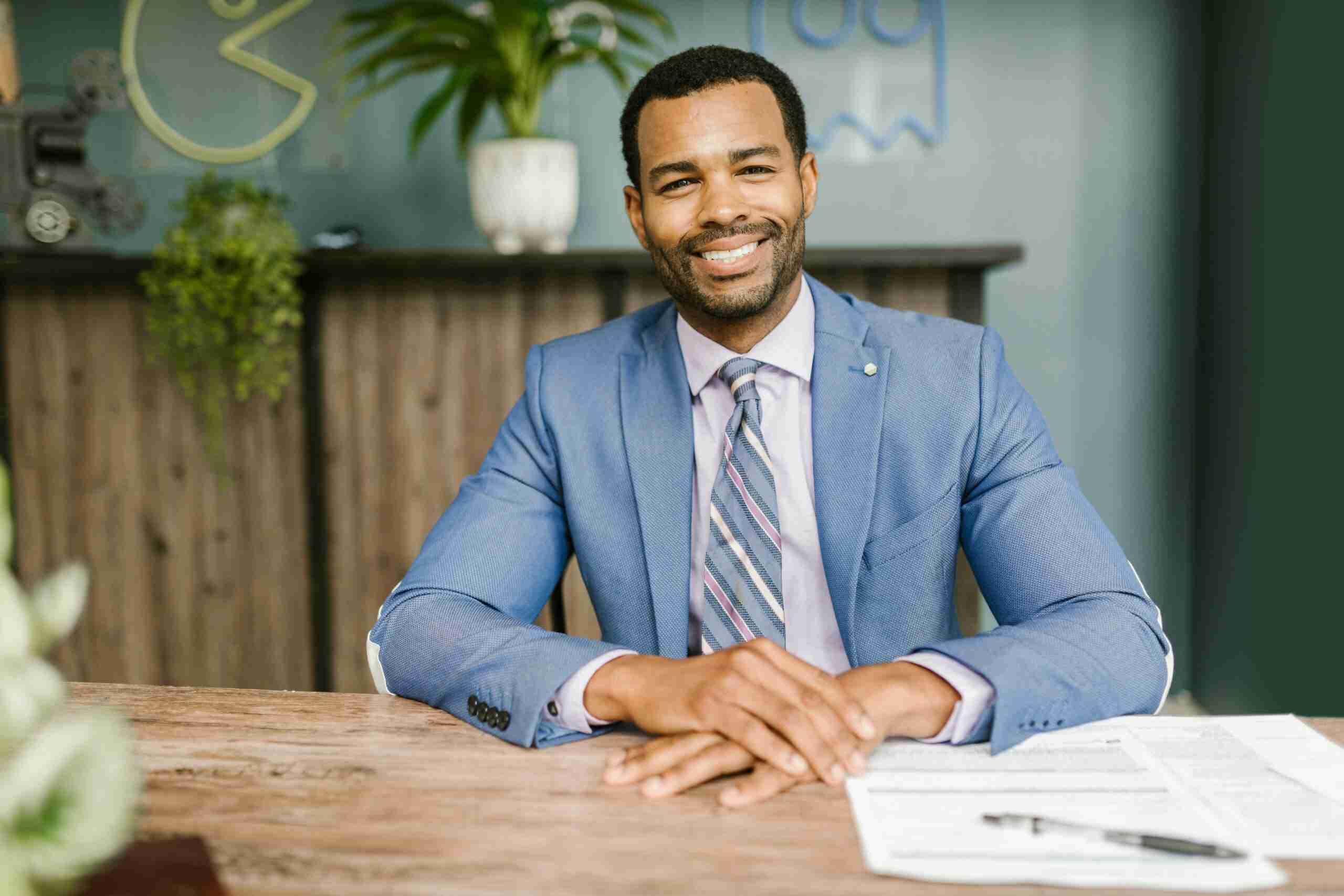 insurance crm Smiling businessman in office attire sitting at a desk with documents.