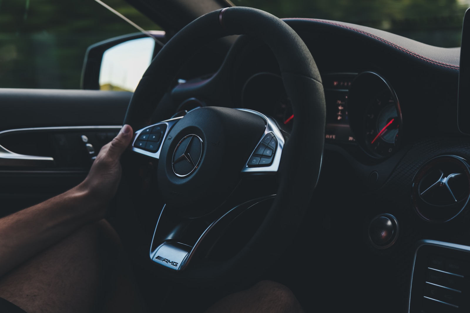person holding on black steering wheel inside car